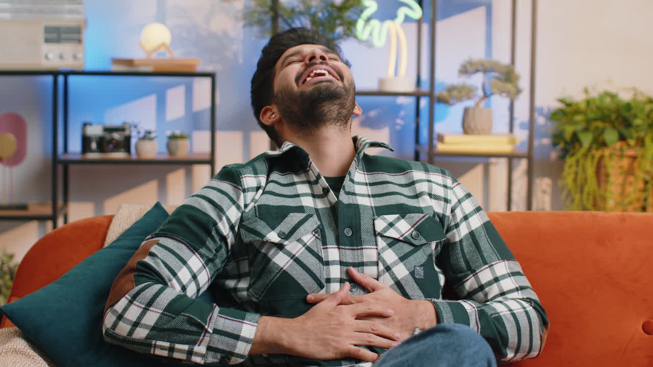 Indian man laughing out loud after hearing ridiculous anecdote funny joke feeling carefree amused