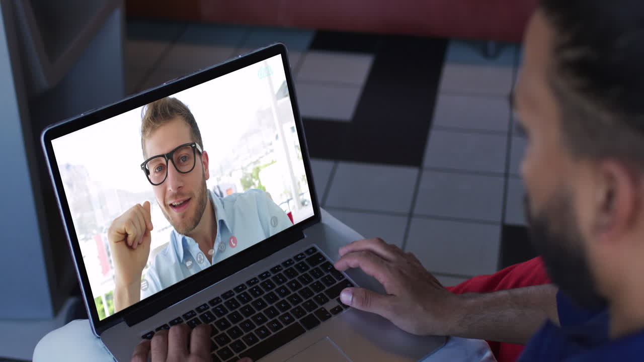hombre afroamericano teniendo una videollamada con un colega de oficina masculino en una computadora portátil en casa