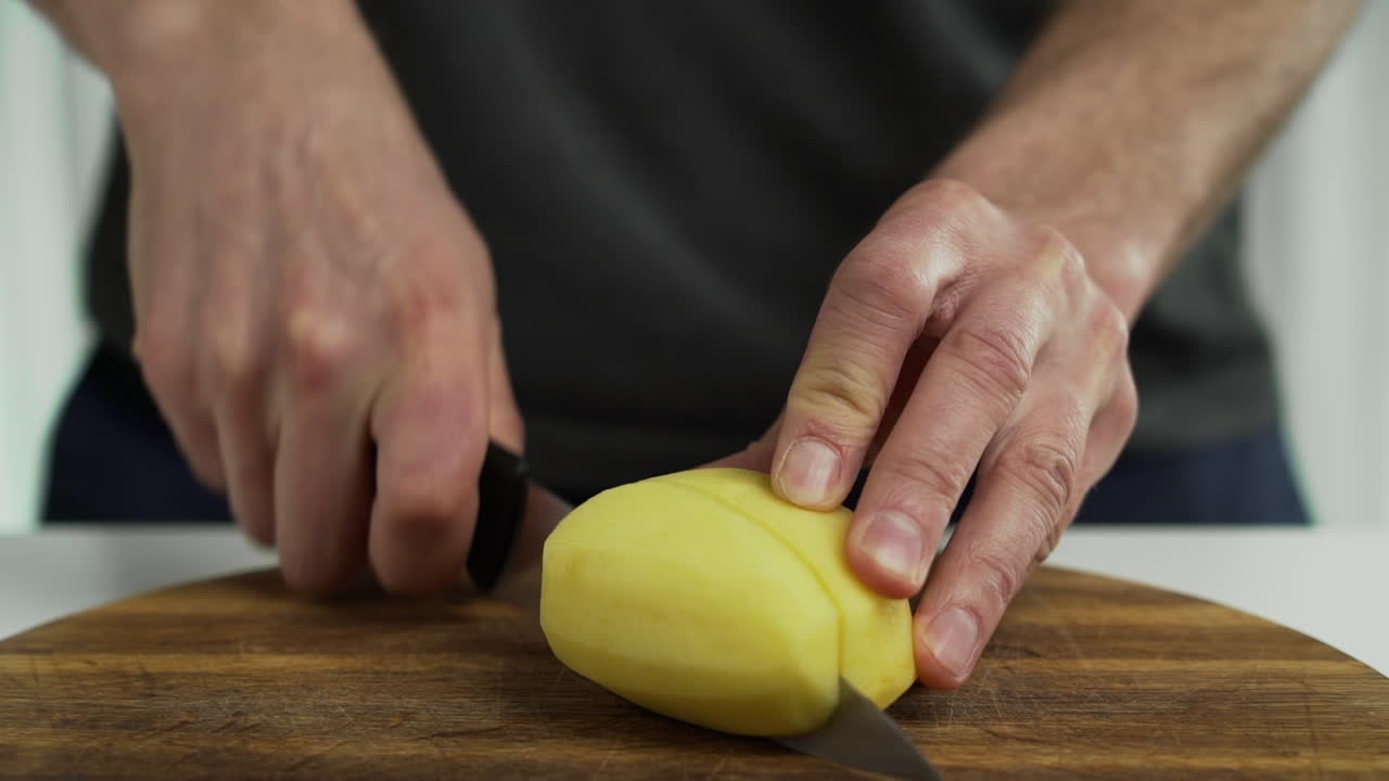 persona cortando gajos de patata en una tabla de cortar en casa, primer plano
