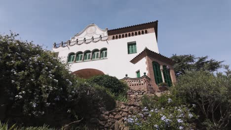 a charming view of park güell's casa trias with vibrant greenery and rustic stonework, barcelona