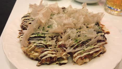 Okonomiyaki---Una-Deliciosa-Comida-Japonesa-Con-Decoración-Dashi-En-Movimiento-En-La-Parte-Superior