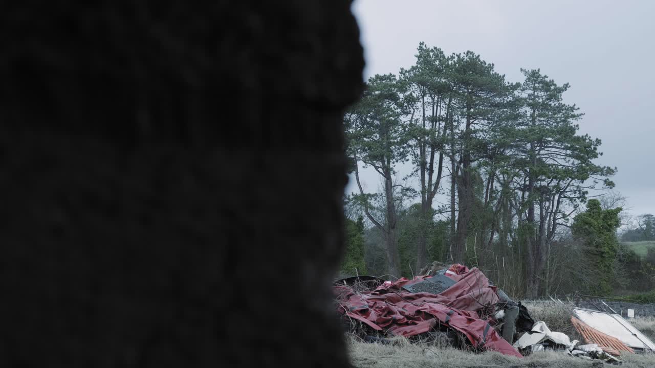 Rubbish And Discarded Things Piled Behind The Concrete Wall And In Front Of The Woods In Ireland. -wide shot