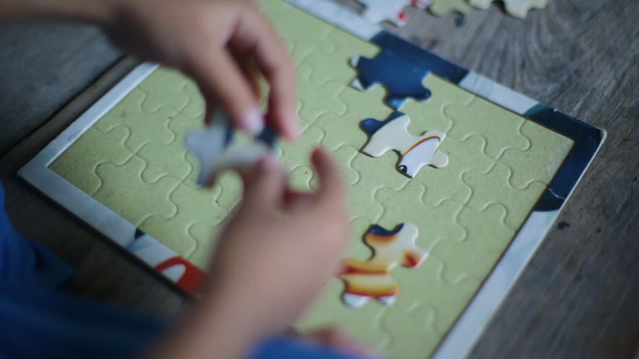 초점을 선택하여 나무 배경에 직소 퍼즐을 푸는 어린 소녀