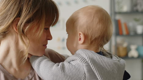 portrait of joyous mother with baby son on arms