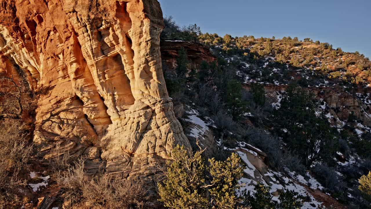 Drone gliding over a striking red rock arch, illuminated by the first light of day near Kanab, Utah.