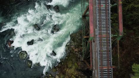 Cascadas-De-Ríos-Bajo-El-Puente-Del-Ferrocarril,-Vuelo-Inverso-Con-Pan-Up