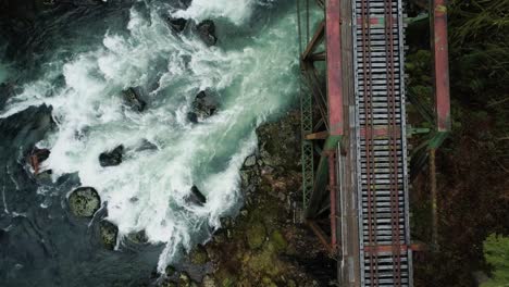 cascadas de río bajo el puente del ferrocarril, vuelo inverso con panorámica hacia arriba
