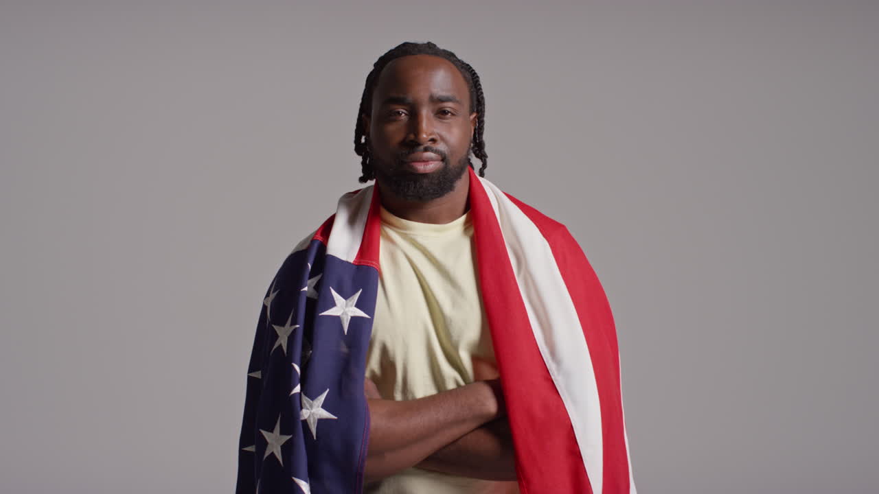 retrato de estudio de un hombre envuelto en la bandera estadounidense celebrando el 4 de julio, día de la independencia.