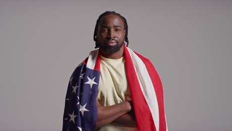 retrato de estudio de un hombre envuelto en la bandera estadounidense celebrando el 4 de julio, día de la independencia.