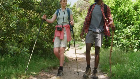 happy diverse couple hiking with backpacks in park, slow motion