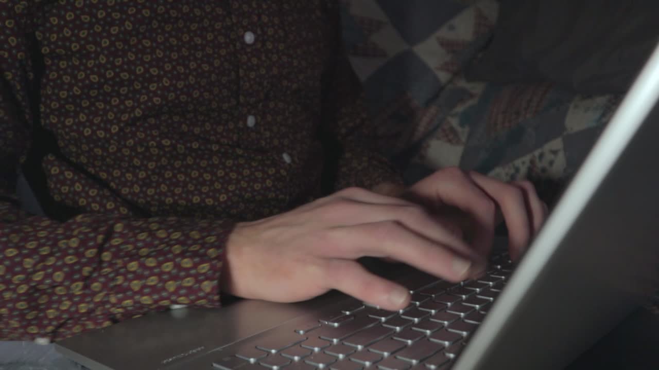 A medium shot of someone typing at their laptop keyboard