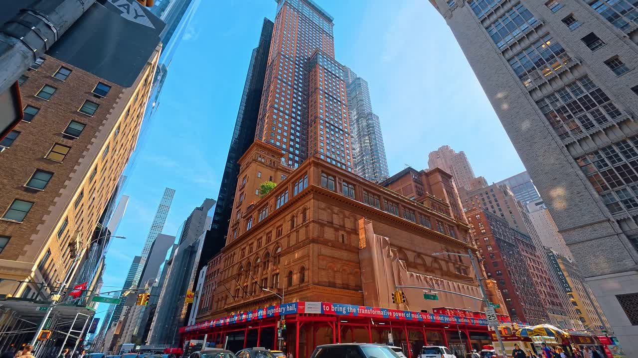 New York, ABD, 1 Nisan 2026: Midtown New York'ta Carnegie Hall ve gökdelenlerin yukarıya doğru çekilmiş perspektifi. Manhattan'daki tarihi tuğla mimarisi ile modern cam kuleler arasındaki zıtlığı gösteren aşırı düşük açılı bir görünüm.