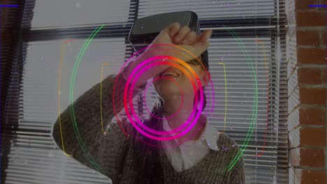 rastros de luz sobre el escáner de alcance contra la mujer asiática gesticulando mientras usa auriculares vr en la oficina
