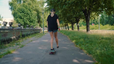 girl rides a skateboard on the street in a summer park