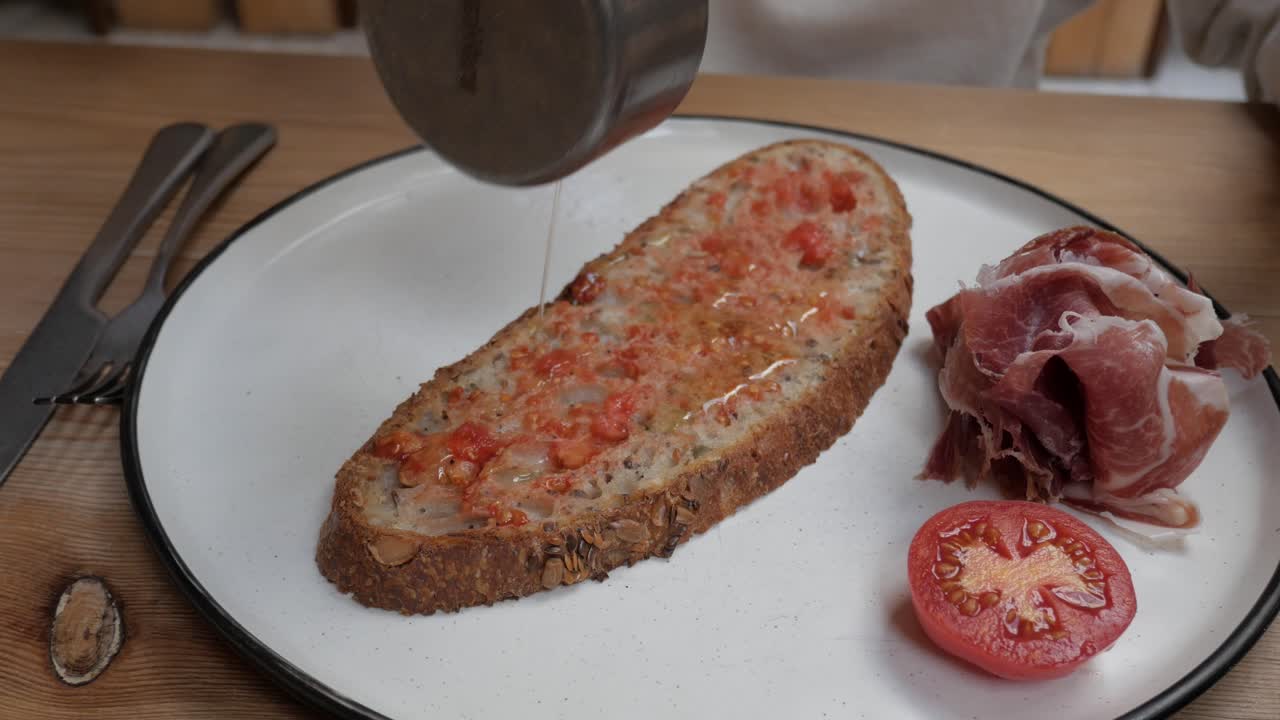 Fresh tomato and ham toast being prepared, with hand pressing down on it