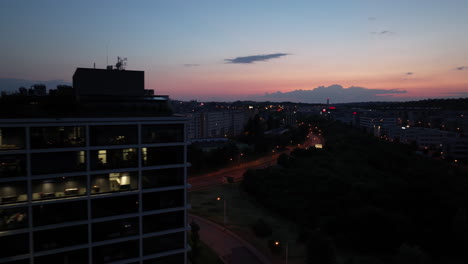 aerial view of prague suburbs at night, sunset sky, street traffic and buildings in lights, czech republic