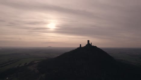 Filmische-Drohnenaufnahme,-Mittelalterliche-Burg-Auf-Einem-Hügel-Als-Sonnenuntergänge-Am-Horizont