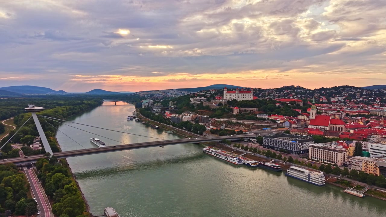 Udsigt over broer og bygninger nær floden under solnedgang i Bratislava.