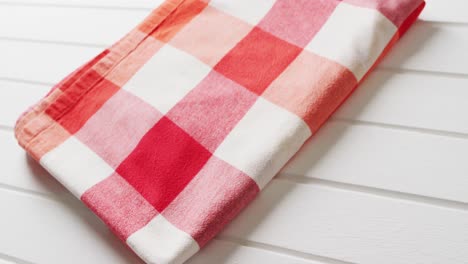 close up of folded red and white checkered blanket on white background with copy space