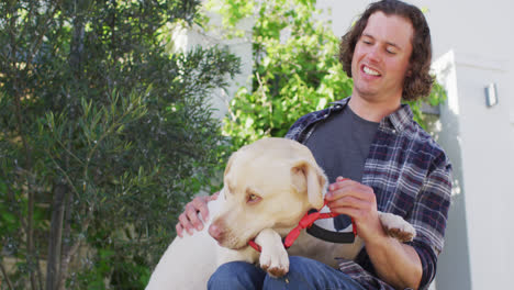 Smiling-caucasian-disabled-man-in-wheelchair-playing-with-pet-dog-in-street