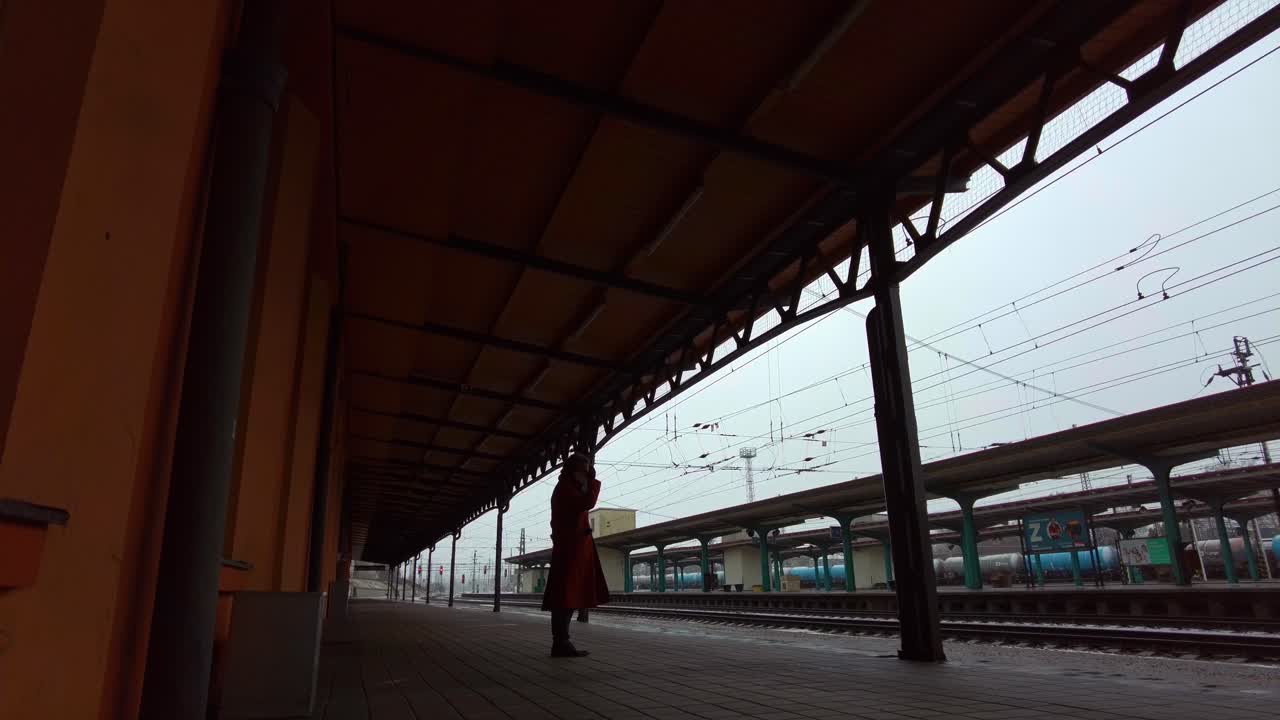 Passenger in winter coat waiting at the train station for the transport train in winter