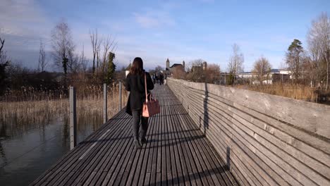 following shot of a young asian woman with black clothes walking on a pier in slow motion in rapperswil switzerland