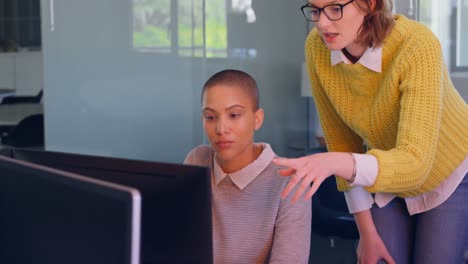 Young-caucasian-female-executives-discussing-over-desktop-pc-in-modern-office-4k