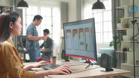 asian female mobile application developer works with graphics on her personal computer in office