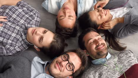imágenes de video de 4k de un grupo de hombres de negocios tendidos en el suelo y escuchando música en una oficina moderna