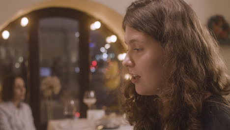 close up of a curly woman singing and playing piano at restaurant