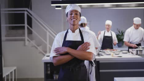 african american female cook working in a restaurant kitchen looking at camera and smiling