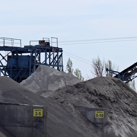 piles of gravel outdoors. industrial factory for production construction materials. metal construction for crashing stones and rocks.