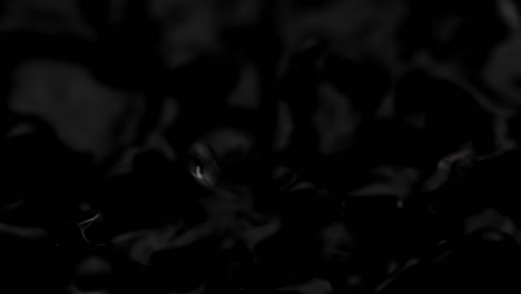 spritzer und tropfen auf der oberfläche der flüssigkeit. abstrakte schwarze hintergrundwasservibrationen. 4k slow motion 100 fps, prores 422, 10 bit