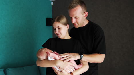new made parents holding their adorable newborn. happy family of three portrait.