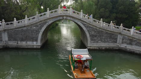 touristic boat navigating under summer place ancient stone bridge in beijing, china