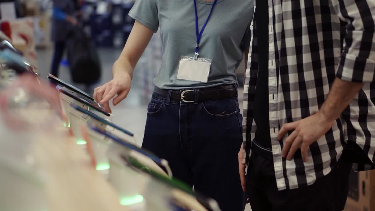 알아보기 힘든 여성 컨설턴트가 새로운 스마트폰을 구입하는 것을 고려하는 크레이드 셔츠를 입은 젊은 남자에게 전문적인 조언을 제공합니다.