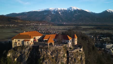 Drone-Sobrevuela-El-Castillo-De-Bled-Con-Los-Hermosos-Alpes-Julianos-Al-Fondo