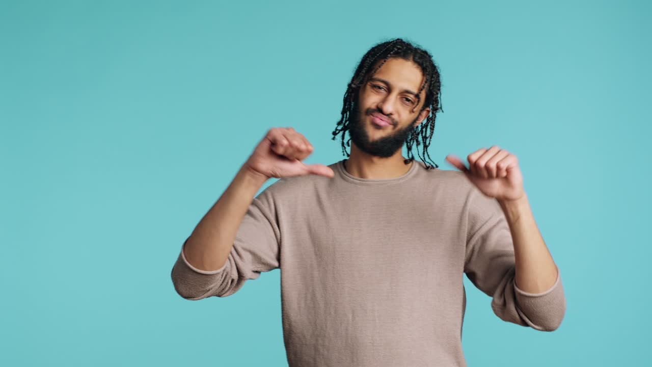 화가 난 남자가 엄지손가락을 내려놓고 몸짓을 하고, 불쾌감을 표하고, 스튜디오 배경