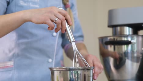 mujer preparando un postre con mezclador y batidor