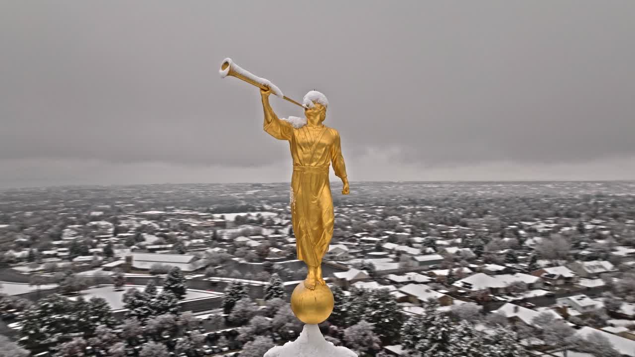 el ángel moroni de oro cubierto de nieve en la trompeta en lo alto del templo mormón de provo.