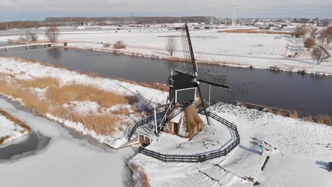 Traditional-Dutch-windmills-in-winter-snow,-cold-winter-aerial-arc-shot