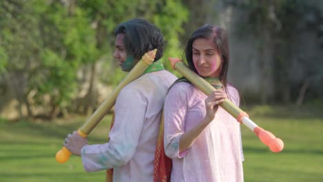 indian couple posing with water gun at a holi festival