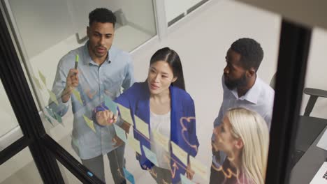 Video-of-four-happy-diverse-male-and-female-colleagues-brainstorming-together-at-night-in-office