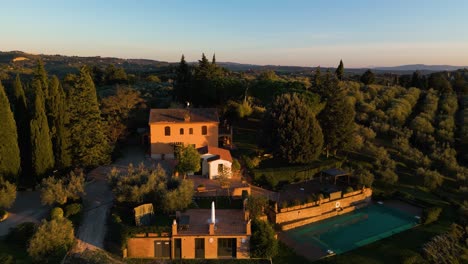 golden hour light spread across classic tuscan villa on outskirts of certaldo amongst olive trees