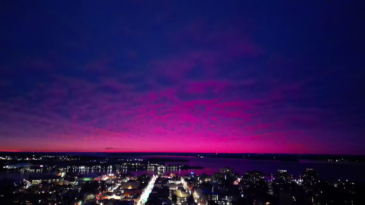 Ripresa aerea con inclinazione verso il basso di un cielo rosa che domina una città.