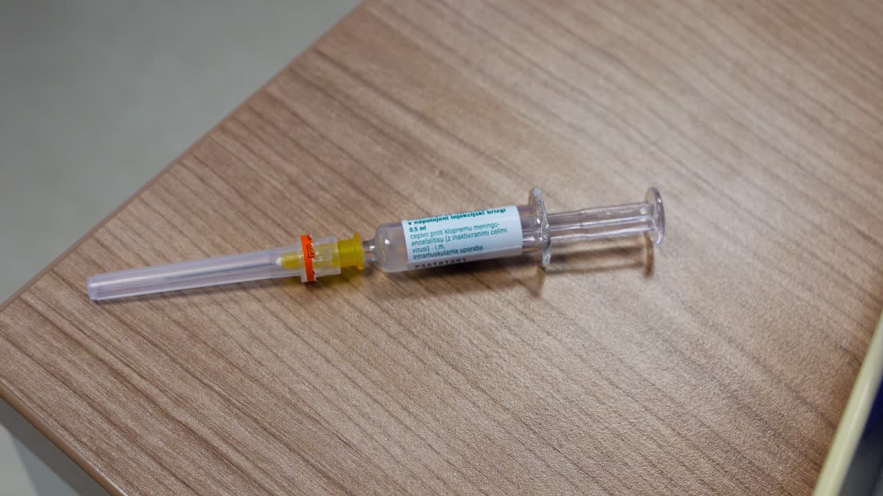 Vaccine syringe on doctor’s desk, TBE dose prepared in sterile setting; top-down close-up