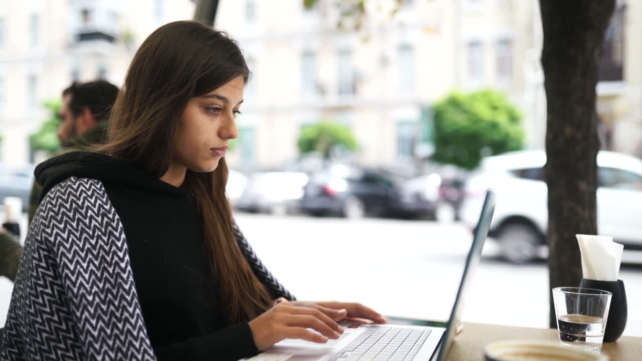 mujer joven trabajando en una computadora portátil en un café