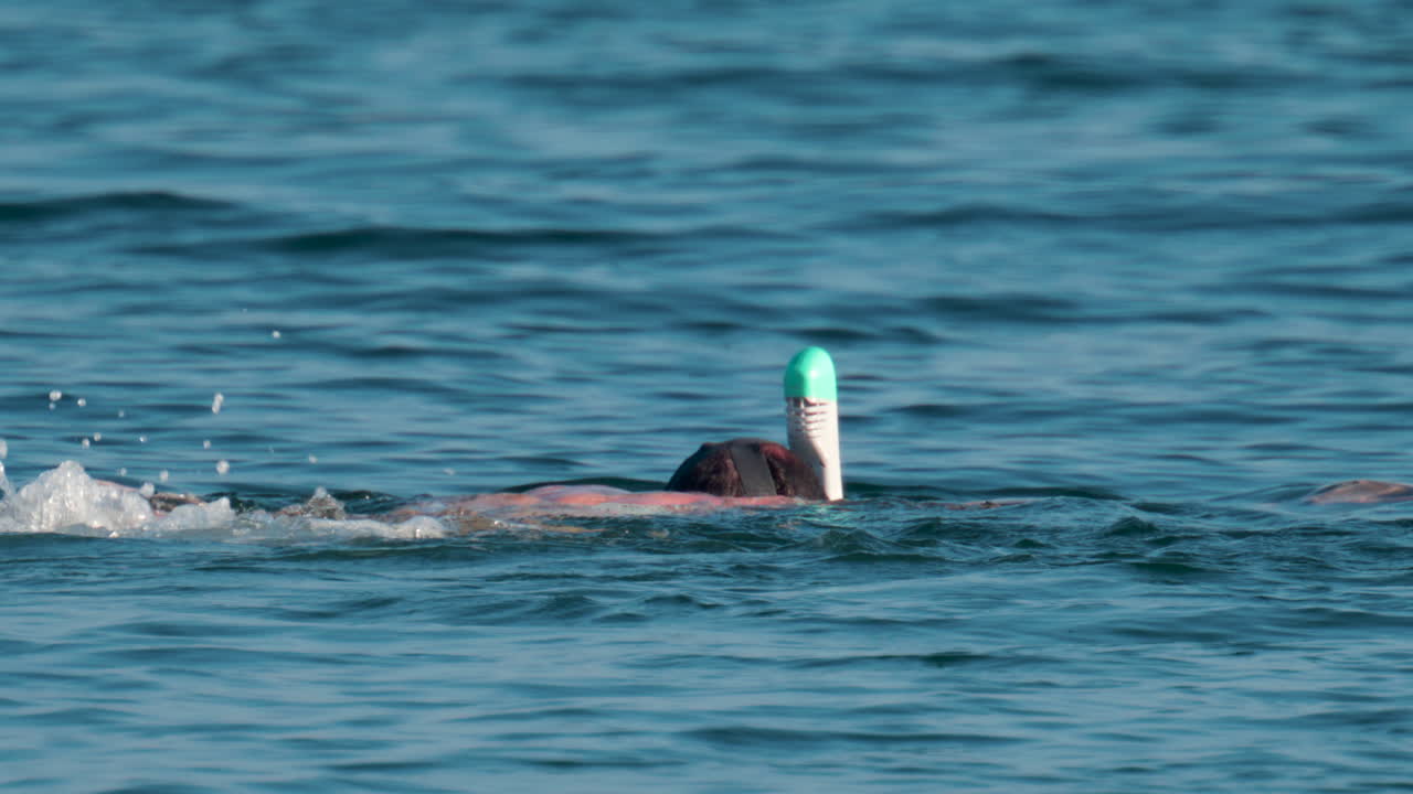 A man wearing a full face snorkel mask floats calmly on the surface of the Mediterranean Sea