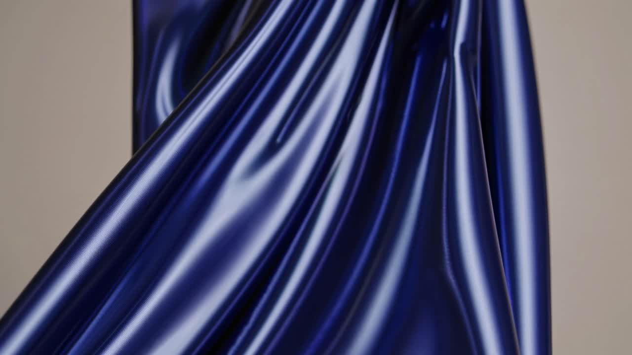 Close-up video of smooth, glossy blue fabric draped elegantly, capturing light reflections