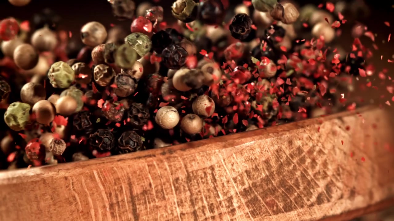 Misto di grani di pepe e fiocchi di peperoncino rosso che cadono al rallentatore